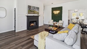 A modern living room with a fireplace, a sofa, a coffee table, and a dining area with chairs. - Boho Chic Retreat Savannah/Dog Friendly/3 BD/2 BATH (Savannah)