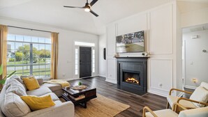 A living room with a sofa, coffee table, and chairs, a fireplace, and a large window with curtains. - Boho Chic Retreat Savannah/Dog Friendly/3 BD/2 BATH (Savannah)