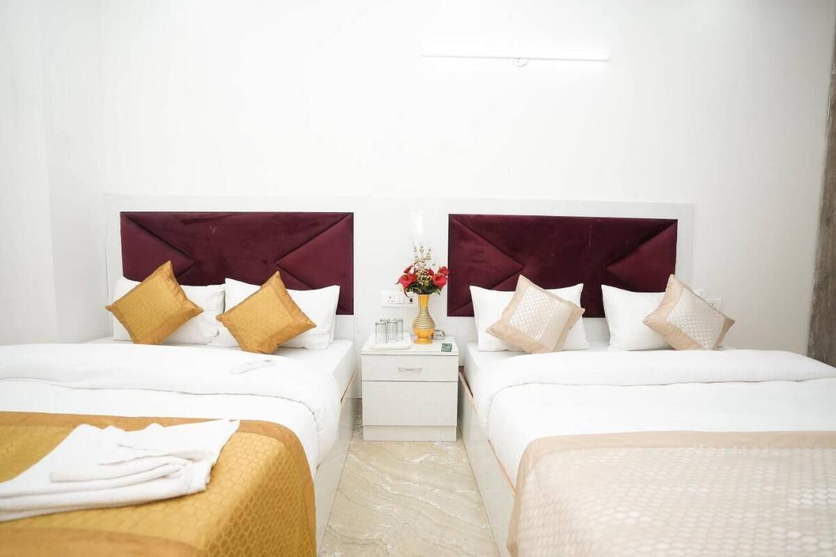 Ein Hotelzimmer mit zwei Betten, jeweils mit einem weißen Kopfteil und einem Marmorboden.