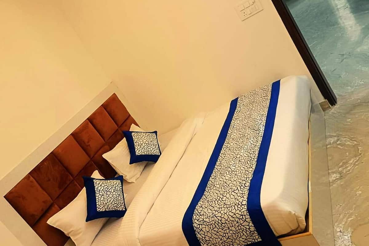 Ein ordentlich bezogenes Bett mit einer blauen und weißen Bettdecke und Kissen, ein Holz-Kopfstück und ein Nachttisch mit einer Lampe.