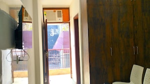 Une chambre d’hôtel dotée d’une grande armoire, d’un téléviseur, d’une table basse en verre et d’un coin salon.