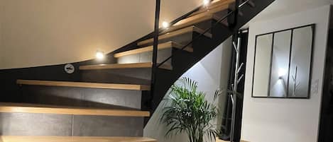 A modern staircase with wooden steps and a black metal railing.