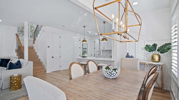 A spacious living area with a wooden dining table, white sofas, and a staircase leading to a kitchen area. - 125 Yards to Private Beach Access. 350 Yards to Gulf Place. Private Pool. LSV. (Santa Rosa Beach)