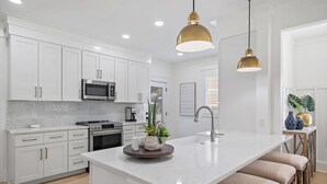 A modern kitchen with white cabinetry, stainless steel appliances, a central island with stools, and pendant lighting. - 125 Yards to Private Beach Access. 350 Yards to Gulf Place. Private Pool. LSV. (Santa Rosa Beach)