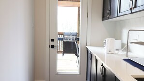 Eine Küche mit integriertem Grill, einer Kaffeemaschine und einem Fenster zu einer Terrassenfläche.