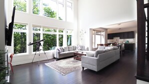 Ein geräumiges Wohnzimmer mit großem Fenster, einer Couch, einem Couchtisch und einem Teleskop.