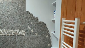 A room with a stone wall, a tiled floor, a small table, and a white radiator. - New single-storey chalet in Gérardmer (Xonrupt-Longemer)