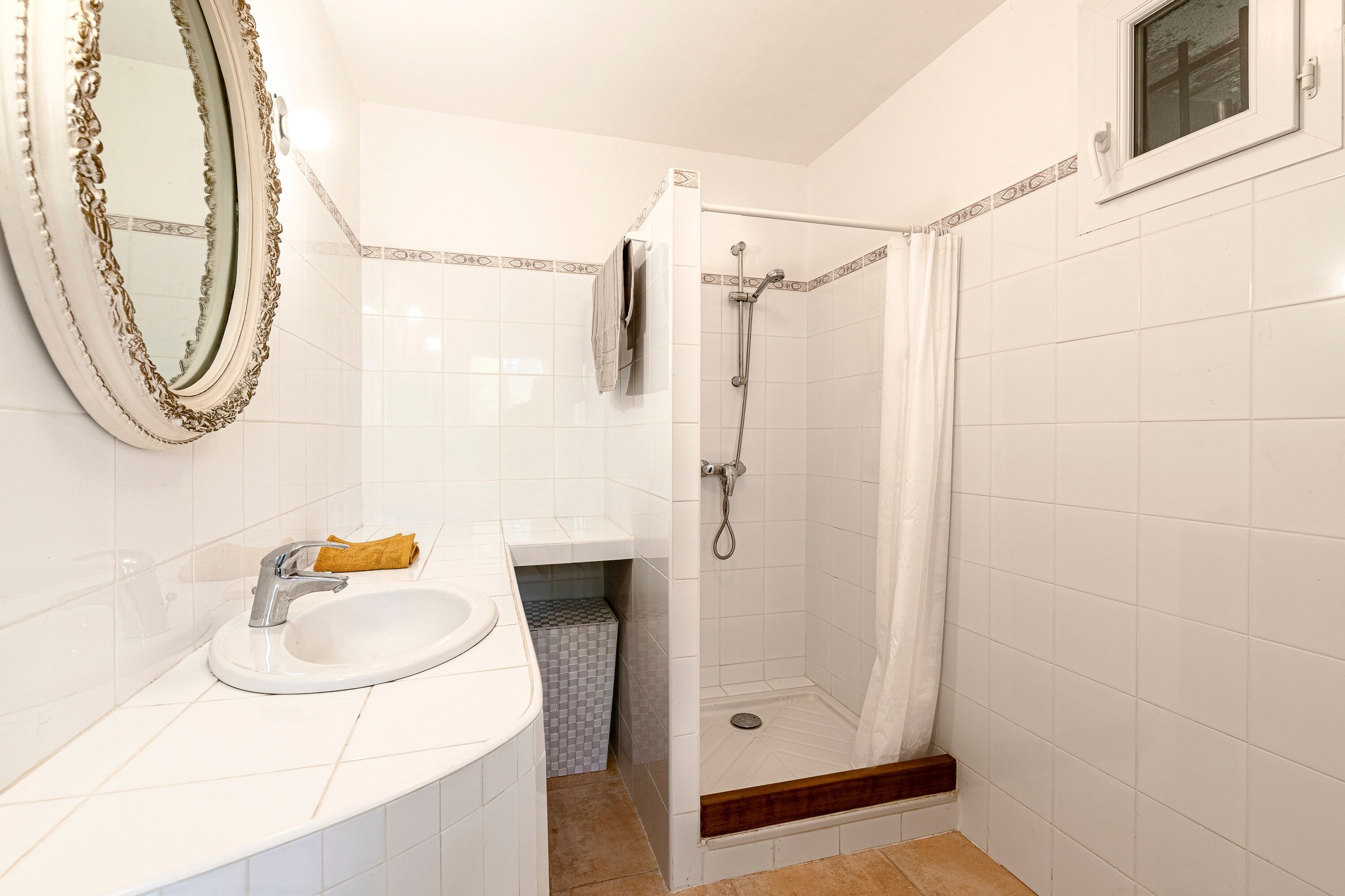 Un baño con lavamanos, espejo, ducha y paredes de azulejos.
