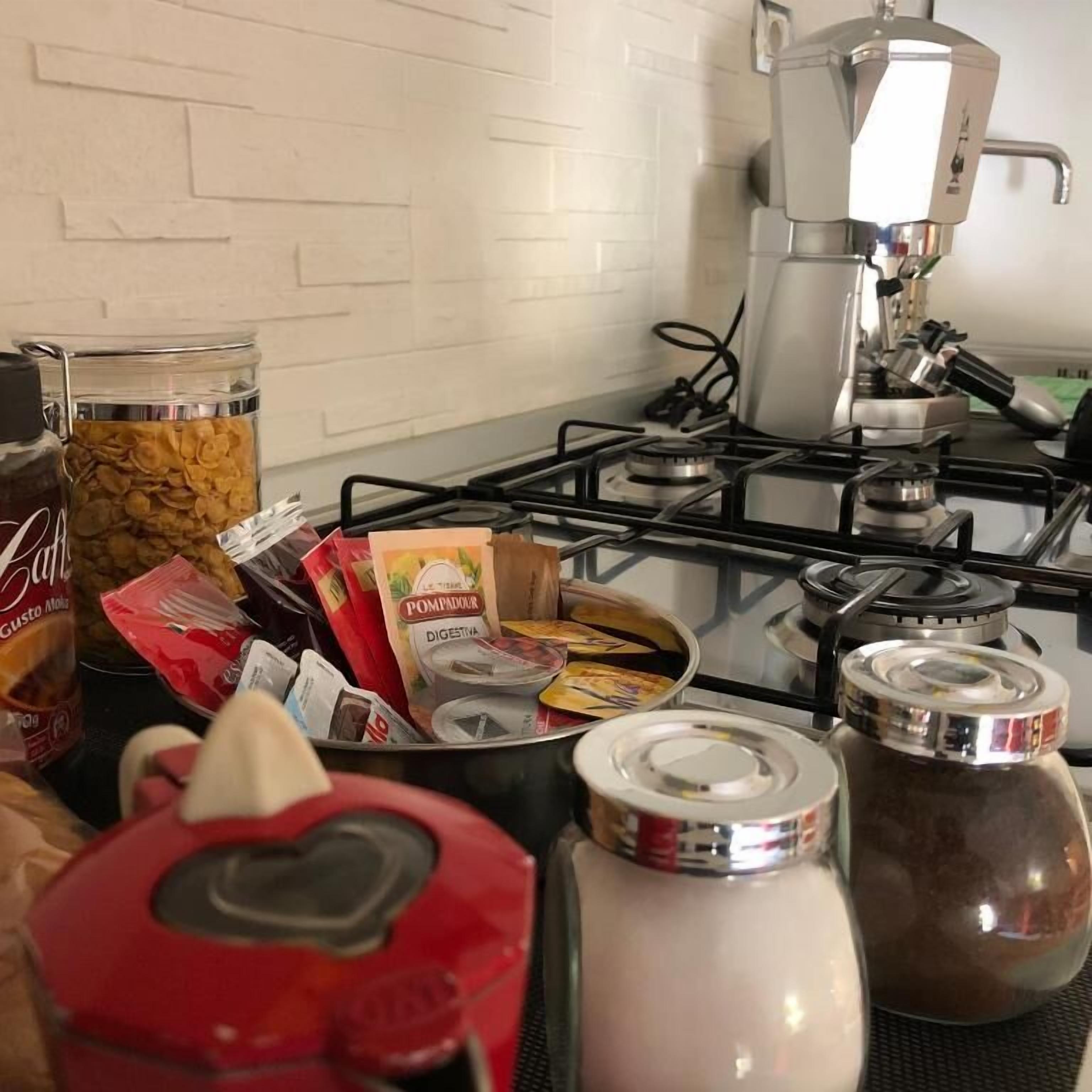Une cuisine équipée d’une cuisinière à gaz, d’une machine à café et de divers produits alimentaires.