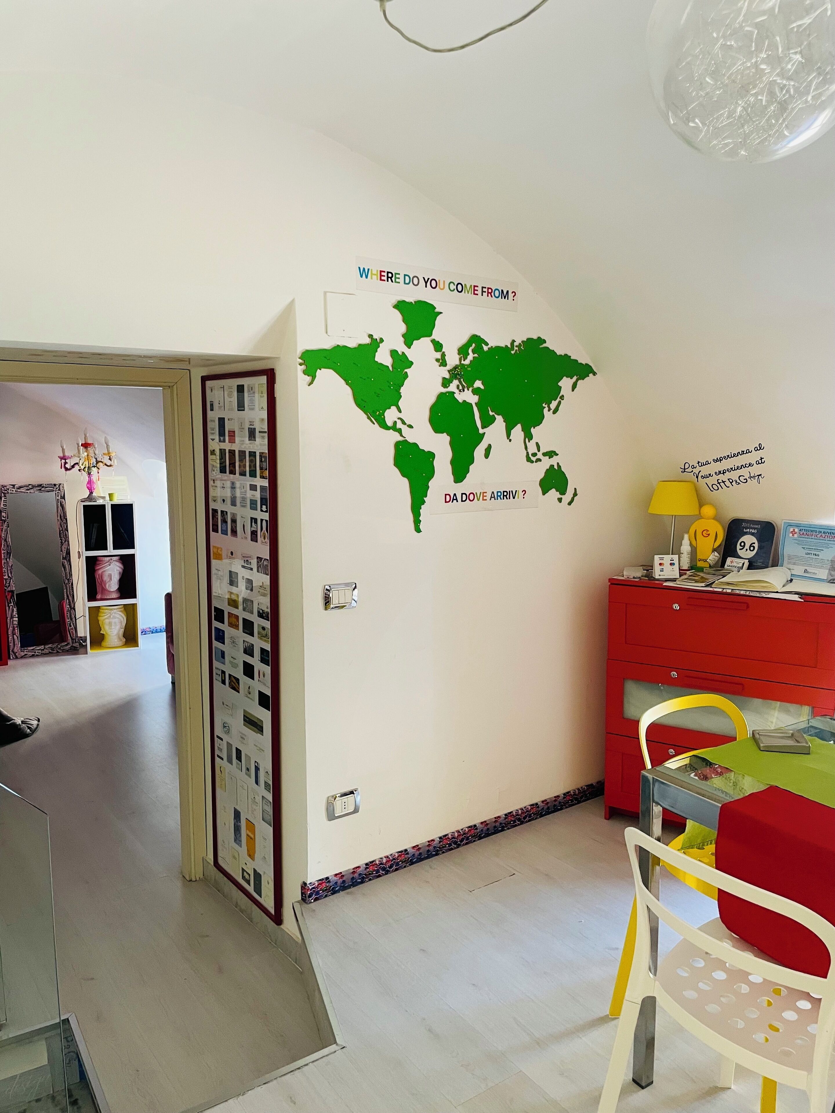 Una habitación con un mural de un mapa mundial, un archivador rojo, una lámpara amarilla y una silla roja.