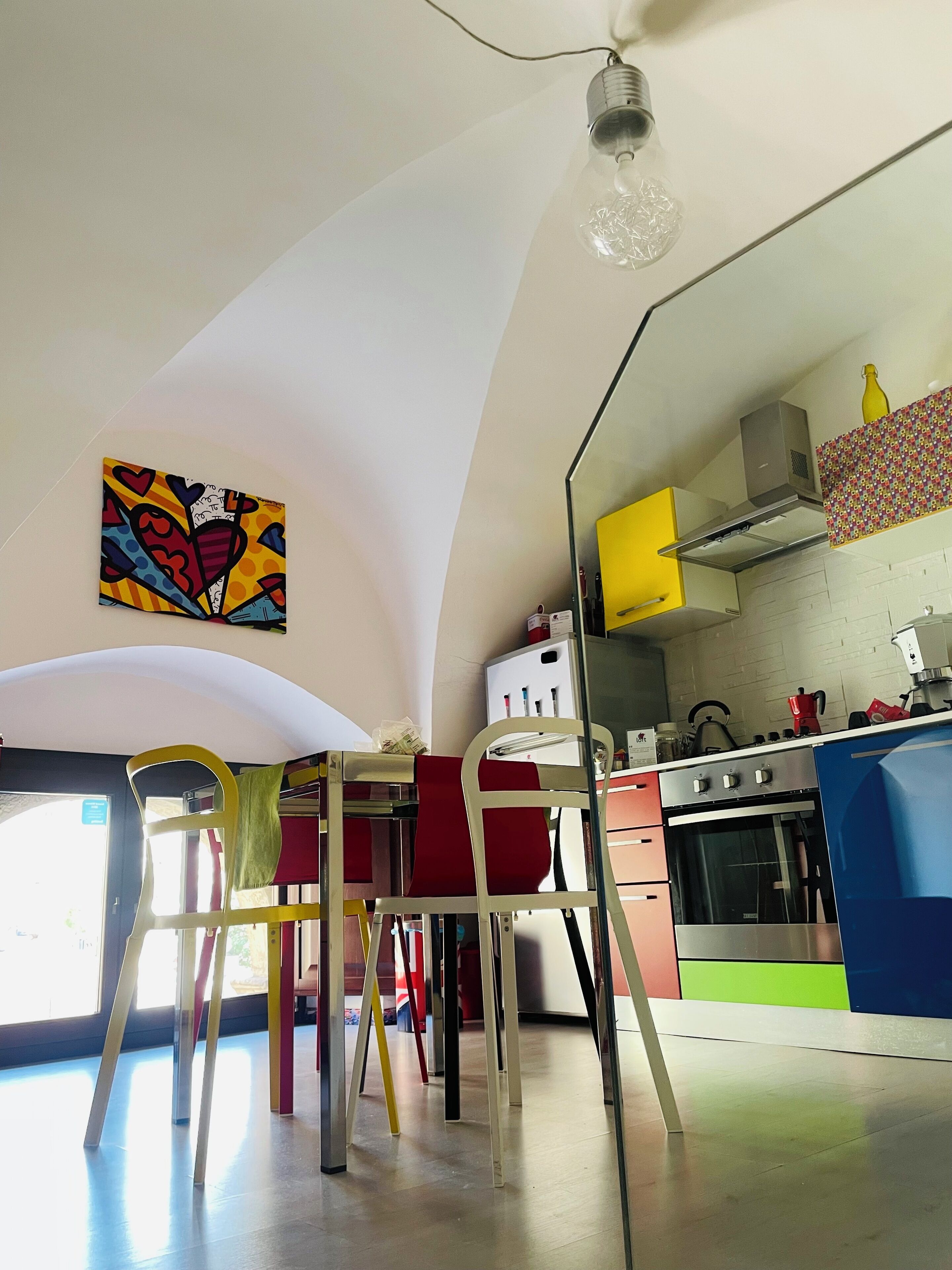 Una cocina con diseño moderno, que destaca por un techo curvo original y una obra de arte colorida en la pared.