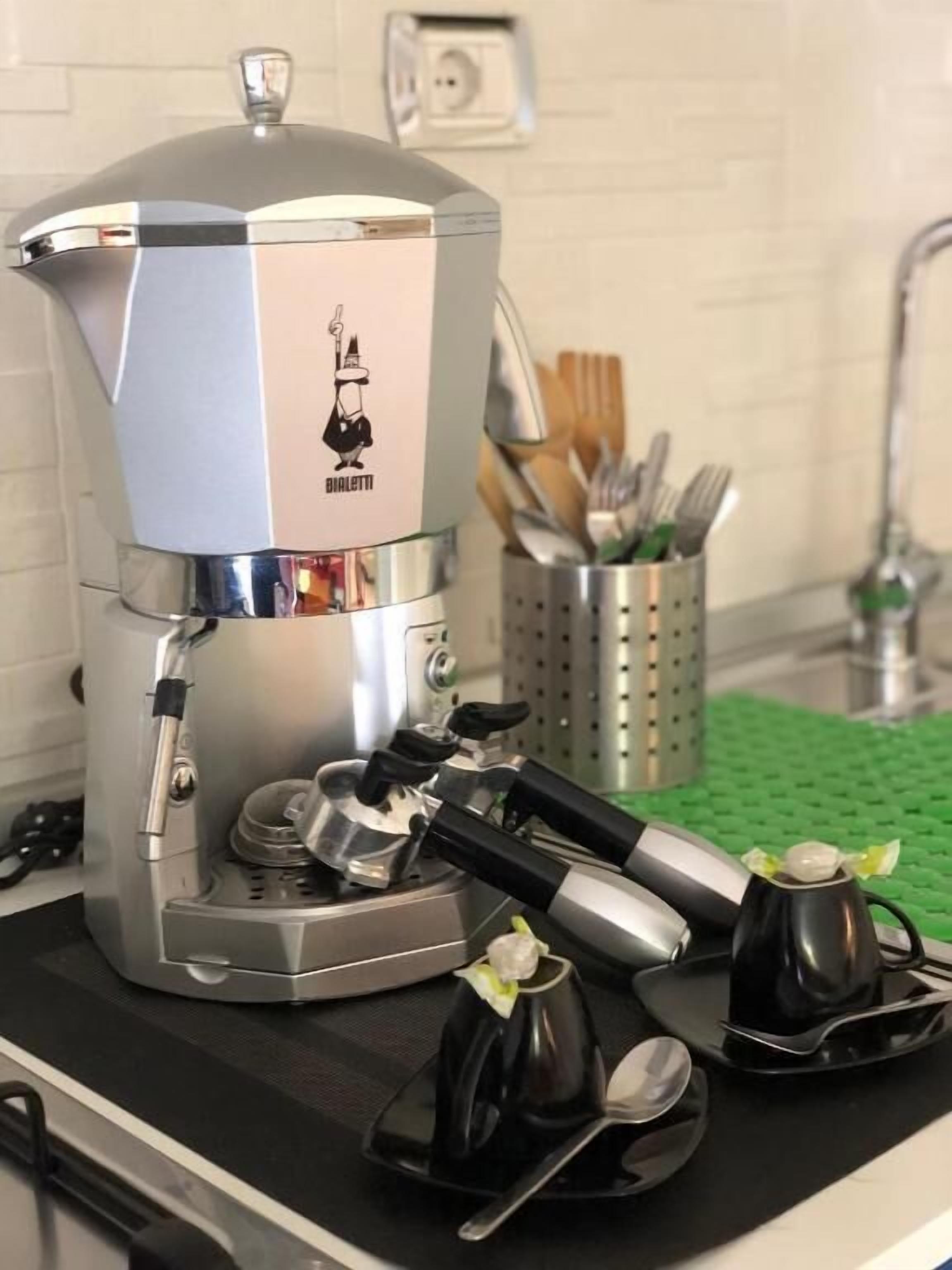 A kitchen with a coffee machine, a sink, and utensils.
