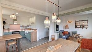 Eine moderne Küche mit einer zentralen Kochinsel, Barhocker und Pendelleuchten.
