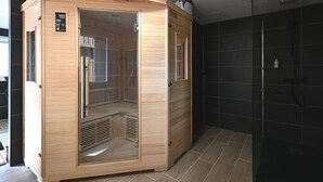 Eine Sauna mit Holzfassade, Bedienfeld und Glastür.