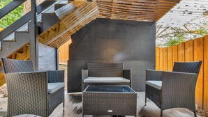 Ett takförsett utomhusområde med sittplatser, möbler av rotting och ett inbyggt bord.
