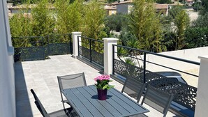 Ein Balkon mit Tisch und Stühlen, einem Blumentopf und Blick auf die Umgebung.