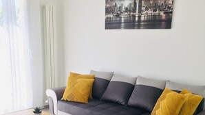 Ein modernes Wohnzimmer mit einer Eckcouch, einem Holztisch und einem Stadtbild an der Wand.