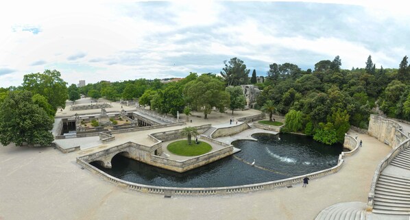 A park with a central water feature, stone bridges, and surrounding greenery.