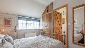 A bedroom with a bed, a wardrobe, a window with curtains, a radiator, and a mirror. - 1 bedroom accommodation in Bognor Regis (Bognor Regis)