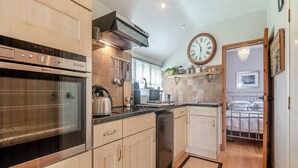 A modern kitchen with stainless steel appliances, wooden cabinets, and a large clock on the wall. - 1 bedroom accommodation in Bognor Regis (Bognor Regis)
