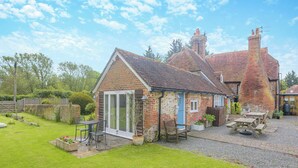 A traditional brick house with a tiled roof, a patio with outdoor furniture, and a well-maintained garden. - 1 bedroom accommodation in Bognor Regis (Bognor Regis)