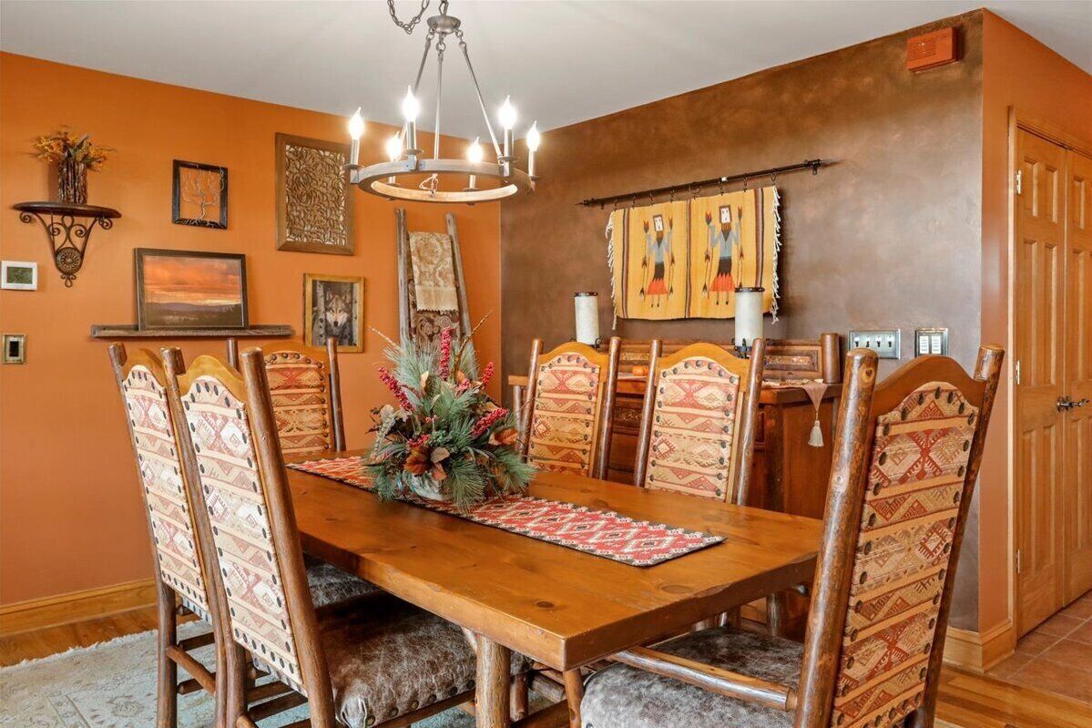 A dining room with a wooden table, patterned chairs, and a chandelier.