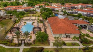Eine Luftaufnahme eines Wohngebiets mit Swimmingpool, Palmen und Häusern mit roten Ziegeldächern.