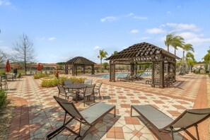 Ein Poolbereich mit Liegestühlen, einer Laube und einer gefliesten Terrasse.