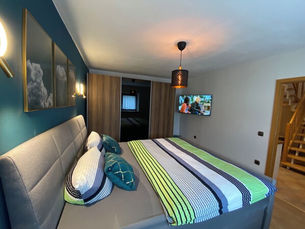 Un dormitorio con cama, sofá, televisión y escalera.
