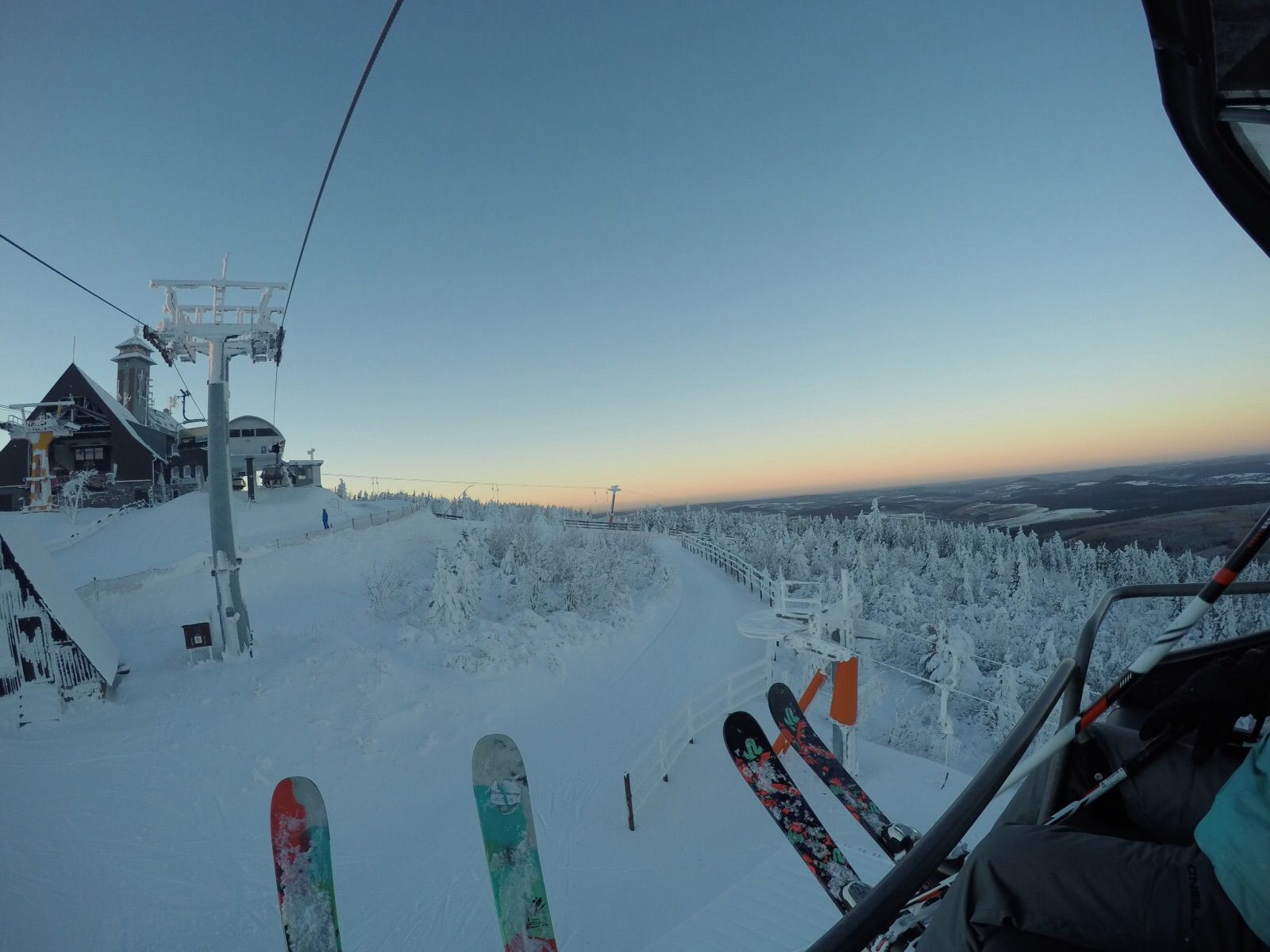 A ski lift with a snowy landscape and a clear sky.