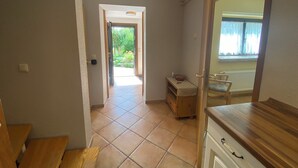 A hallway with a wooden bench, a small table with a bowl, and a view of a garden through an open door. - Gemütliche Ferienwohnung Über 2 Etagen mit Garten und Kamin, Haustierfreundlich! (Oberwiesenthal)