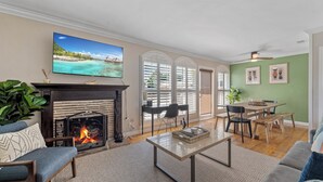 A living room with a fireplace, a television mounted above it, and a dining area with a table and chairs. - Ladoga's Hideway, Gorgeous Pool, Game Room, Fire Pit, Private Backyard,BBQ Grill (Long Beach)