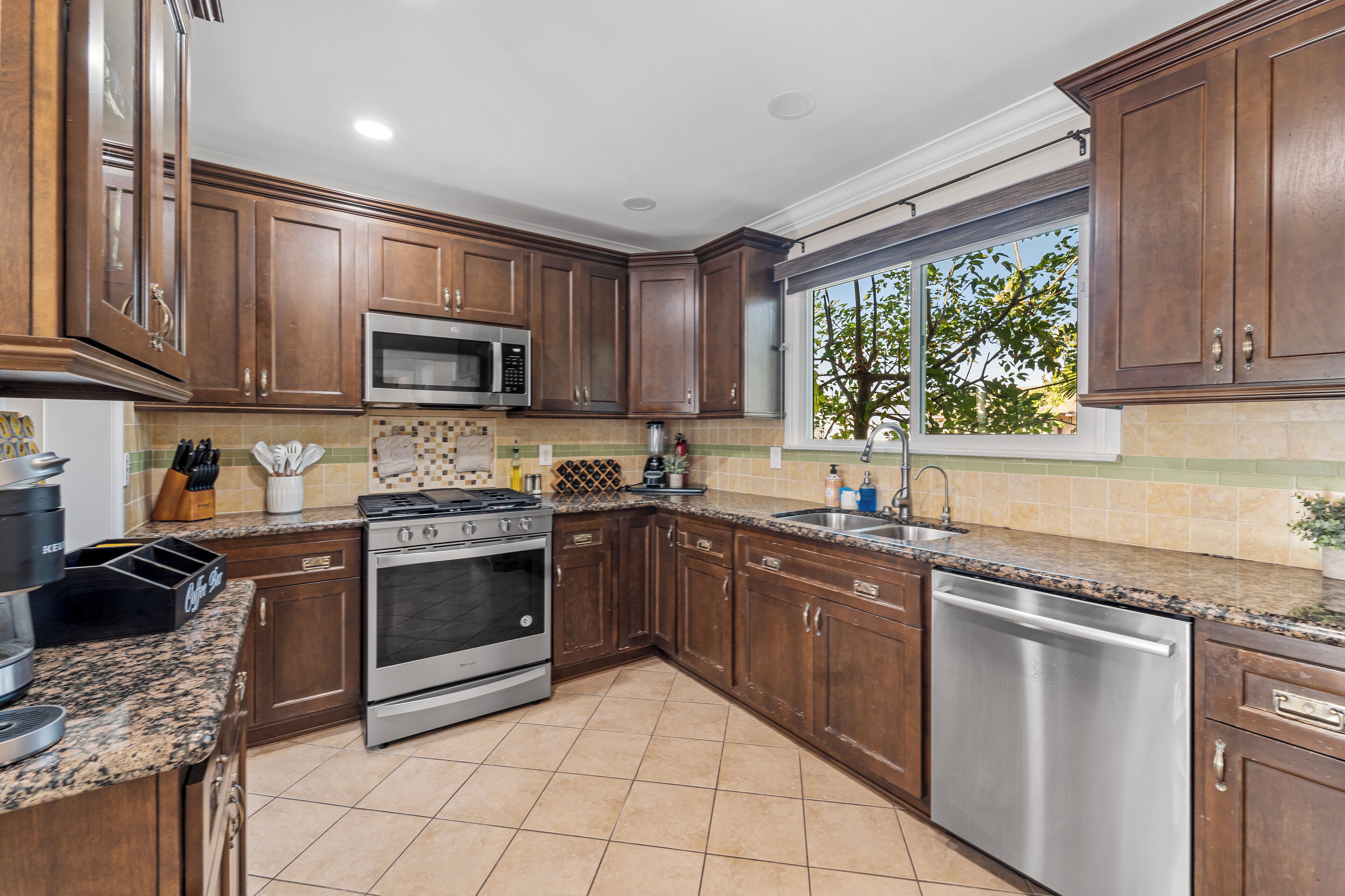 A kitchen with wooden cabinets, stainless steel appliances, and a window with a view of trees.