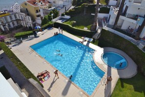 Una piscina circondata da una terrazza con persone che nuotano e si rilassano.