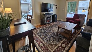 Una sala de estar con chimenea, televisor, mesa de comedor y sofá.