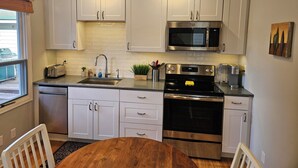 Una cocina moderna con armarios blancos, electrodomésticos de acero inoxidable, un tostador y una cafetera.