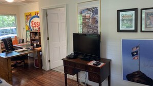 A room with a wooden desk, a television, and a bookshelf. There are posters on the wall and a door leading to another room. - Apartment in Downtown Clemson. Just a few minutes to Campus & Football Stadium. (Clemson)