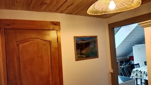 A wooden door, a framed landscape painting, and a dining area with tables and chairs.