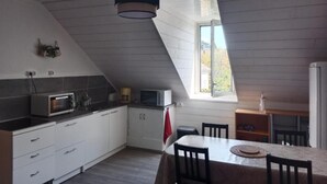 A kitchen with white cabinets, a microwave, a toaster, and a dining table with chairs.