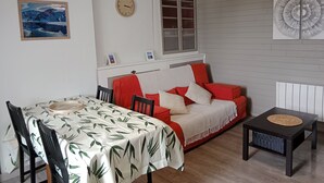 A cozy room with a dining table, chairs, a sofa, and a small table with a woven placemat.
