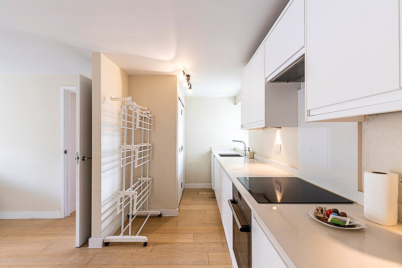 A modern kitchen with white cabinets, a stainless steel sink, and a built-in oven.