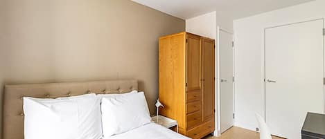 Un dormitorio con cama, armario, escritorio y silla.