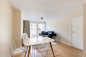 Ein modernes Wohnzimmer mit einem weißen Tisch, Stühlen, einer Couch und einer Tür.