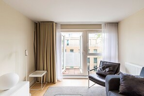 Ein modernes Hotelzimmer mit Balkon, einer Couch, einem kleinen Tisch und einer Heizung.