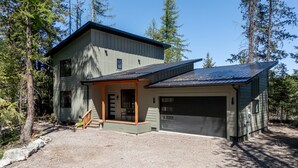A two-story house with a garage, surrounded by trees. - Glacier Natl Park & River Views, Dog Friendly (Hungry Horse)