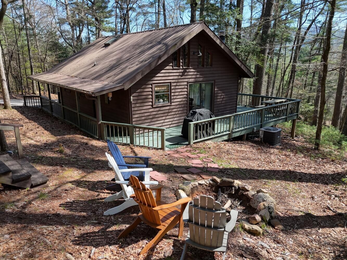 A rustic cabin with a porch, surrounded by trees.