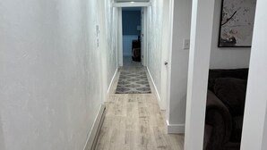 Un couloir doté d’un plancher en bois, de murs blancs et d’un éclairage encastré.