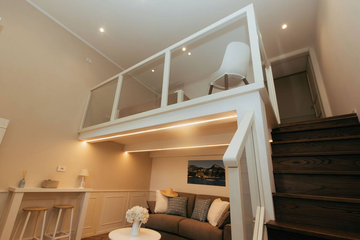 Ein modernes Interieur mit Schlafzimmer im oberen Bereich, einem Essbereich und einer Treppe.