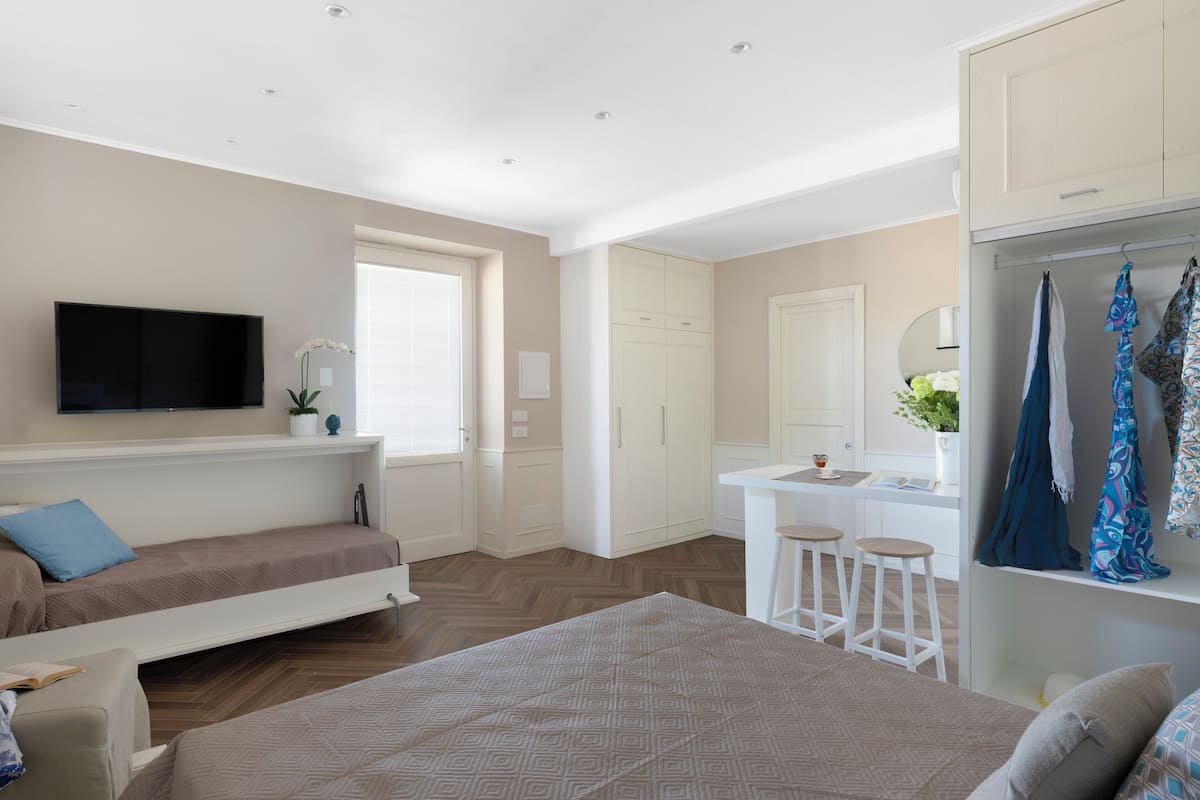 Ein modernes Schlafzimmer mit Bett, Fernseher, Schreibtisch und Kleiderschrank.