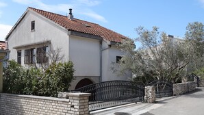 Un edificio de dos pisos con techo de tejas, pared de ladrillo y portón metálico.